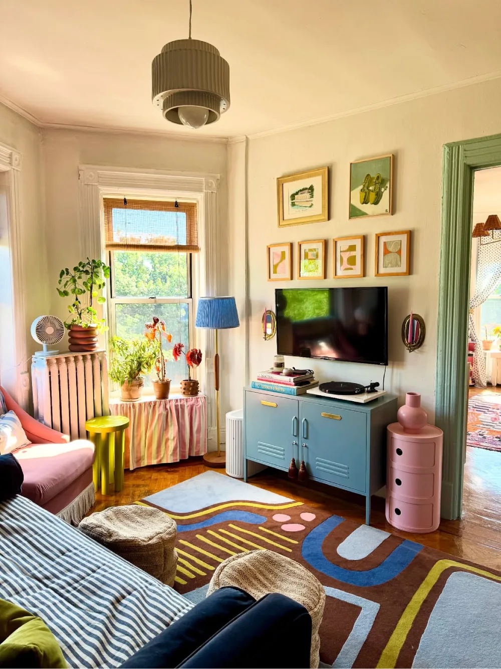 Colorful living room with blue cabinet, patterned rug, and pink accents