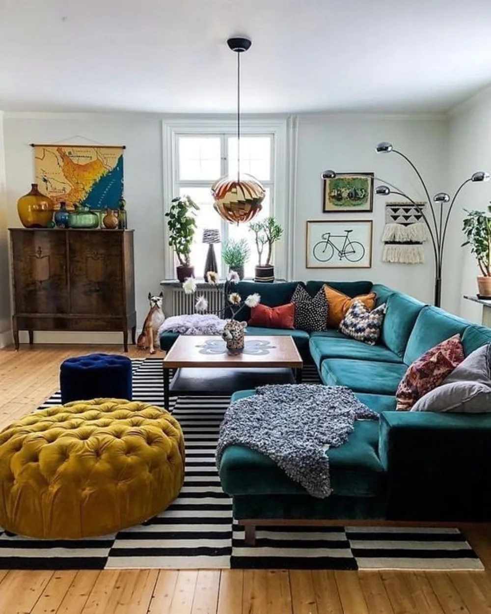 Eclectic living room with teal sectional, mustard ottoman, and graphic rug