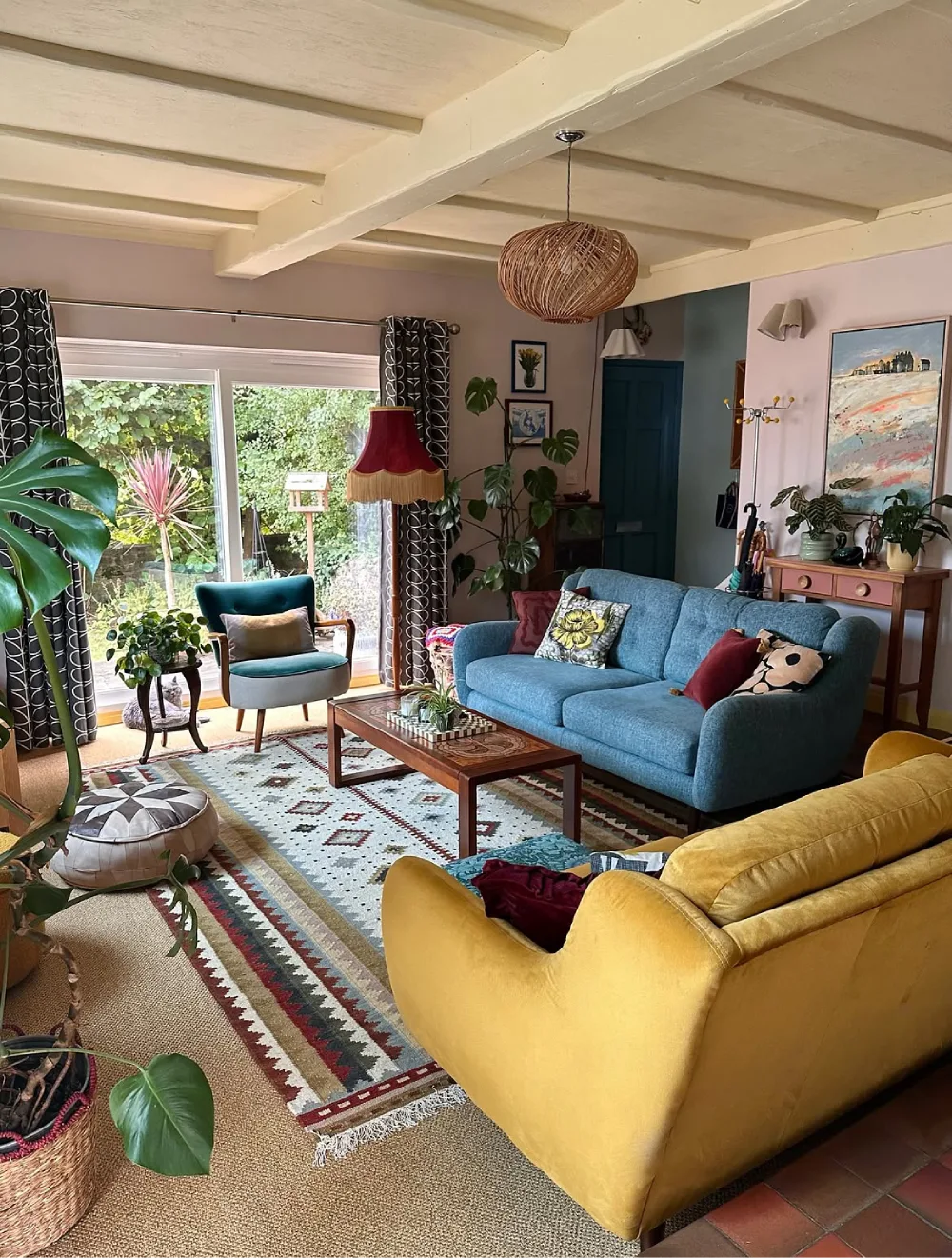 Eclectic living room with blue and yellow sofas, patterned rug, and houseplants