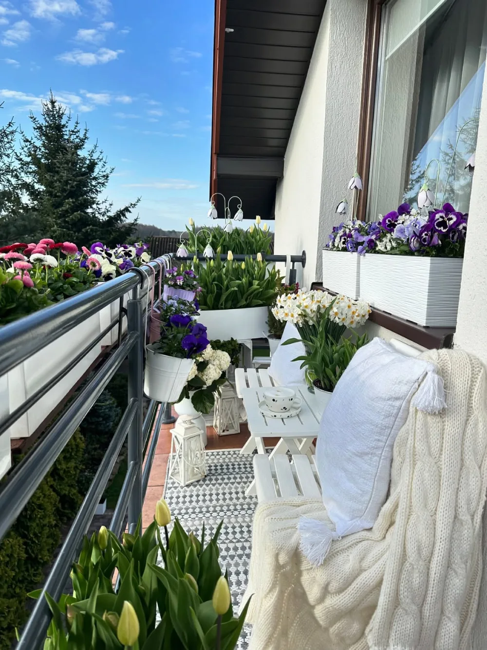 cozy balcony with white seating and colorful potted flowers