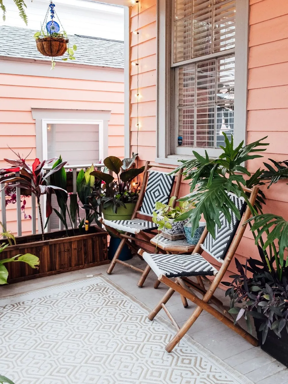 tropical balcony with wooden lounge chairs, plants, and patterned rug