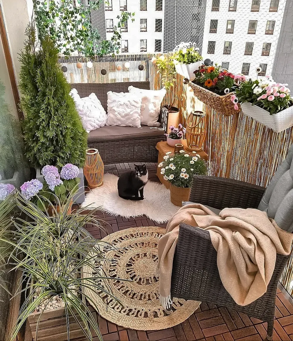 private balcony with wicker seating, flowering plants, and reed privacy screen