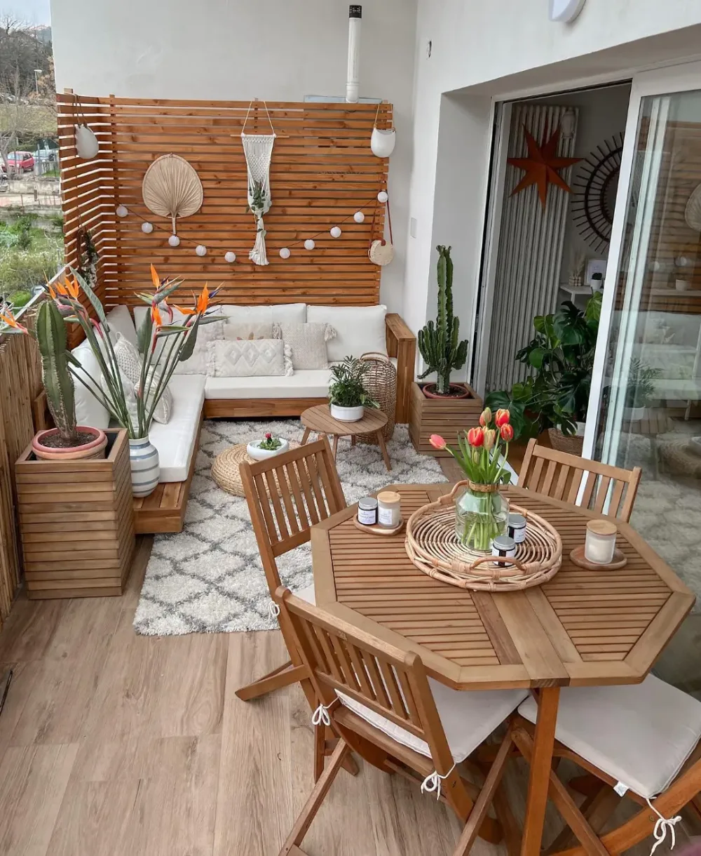 wood balcony lounge with sectional sofa, dining table, plants, and slatted privacy screen