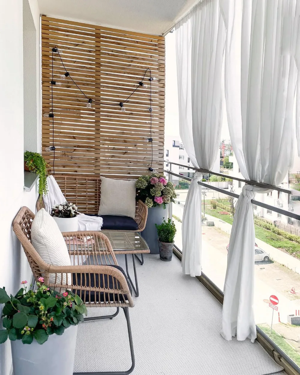 cozy balcony with cushioned bench, candles, plants, and warm string lights