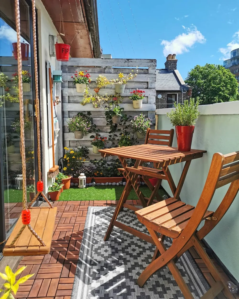 colorful balcony garden with bamboo privacy screen, plants, patterned cushions, and small table