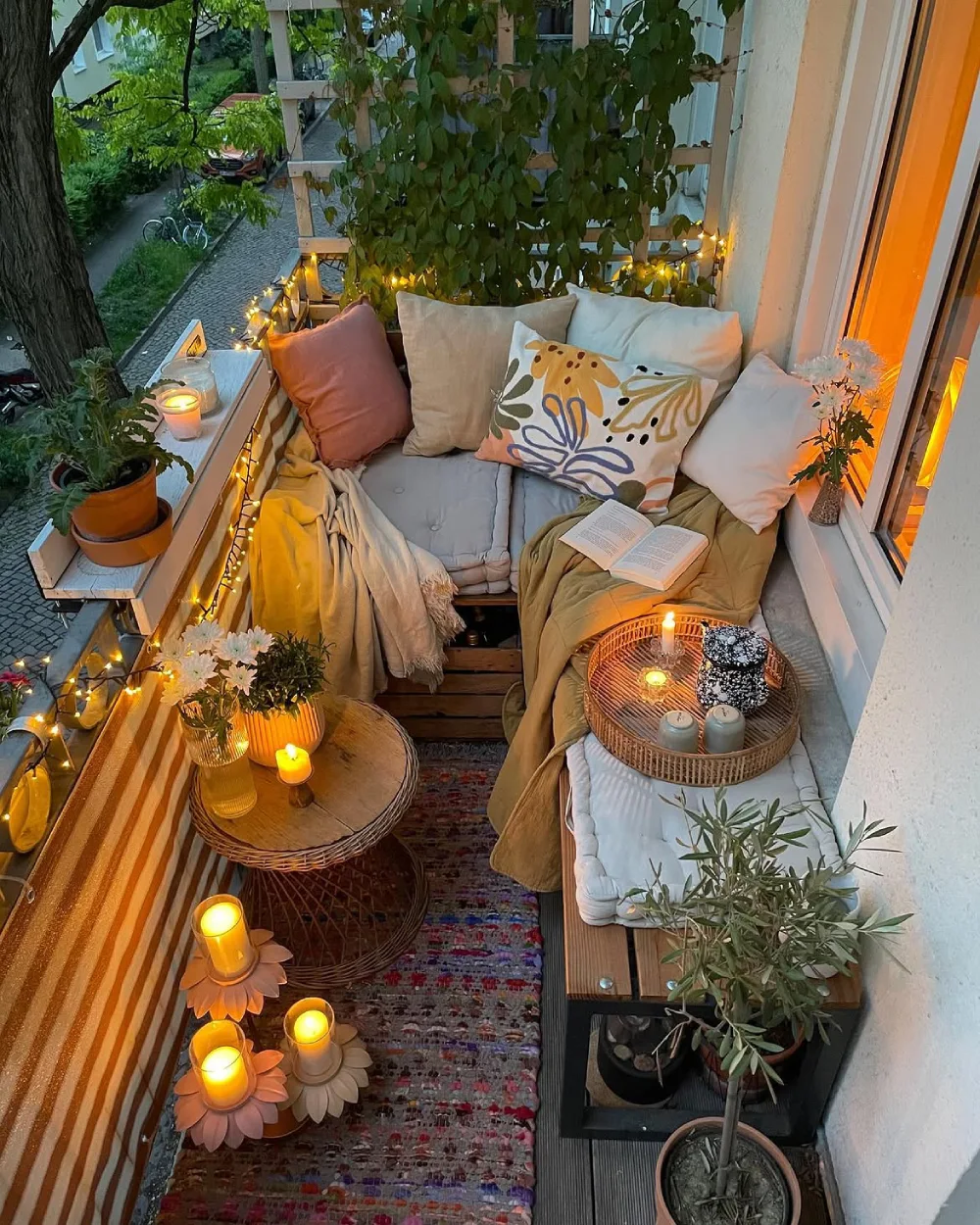 soft balcony reading nook with cushioned bench, pillows, candles, and greenery