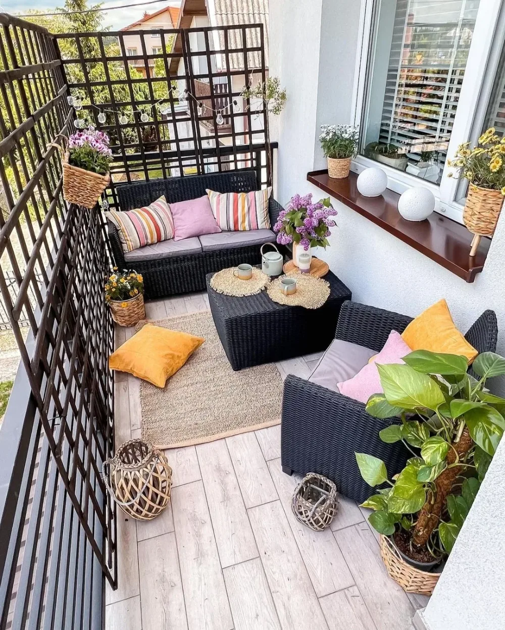 balcony lounge with black wicker furniture, colorful cushions, and plants