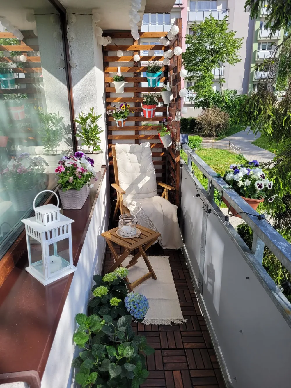 narrow balcony with wooden privacy screen, plants, and lounge chair