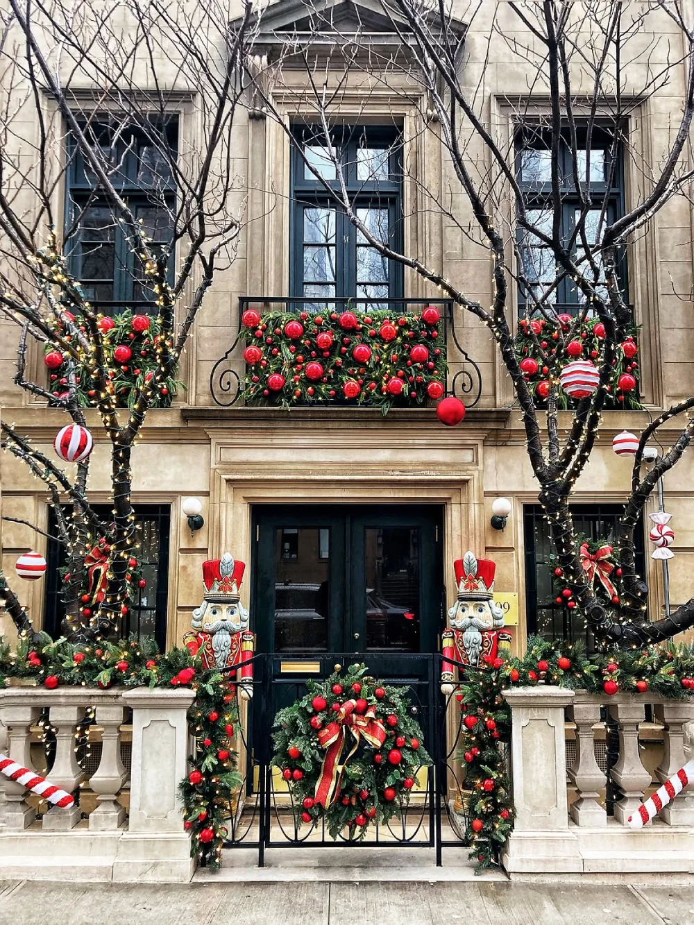 Urban townhouse entrance decorated with Christmas greenery, red ornaments, wreaths, and nutcracker figures