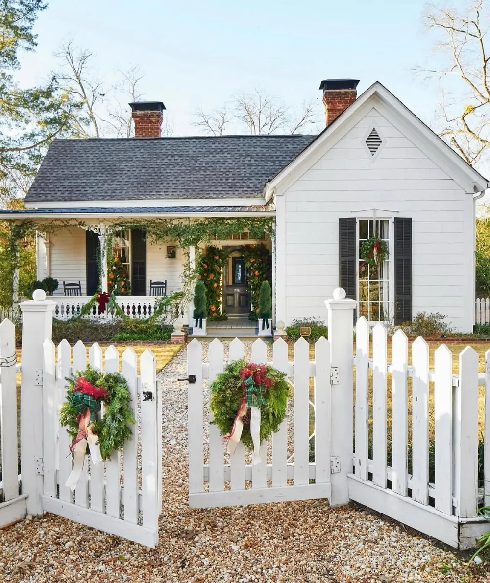 White picket garden gate decorated with Christmas wreaths and greenery