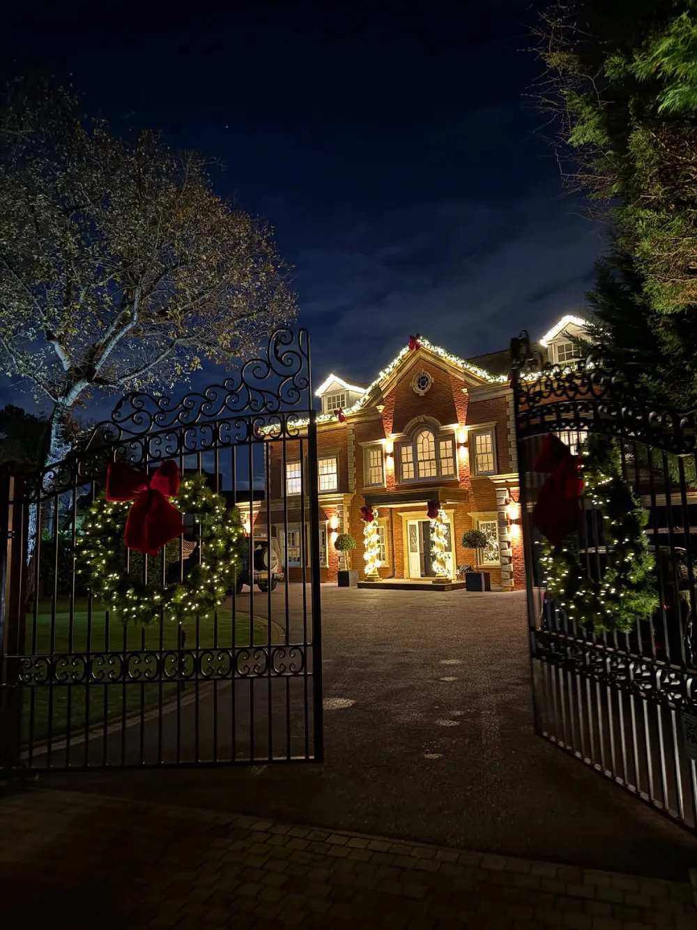 Christmas home entrance decorated with glowing ornaments, string lights, and a festive wreath
