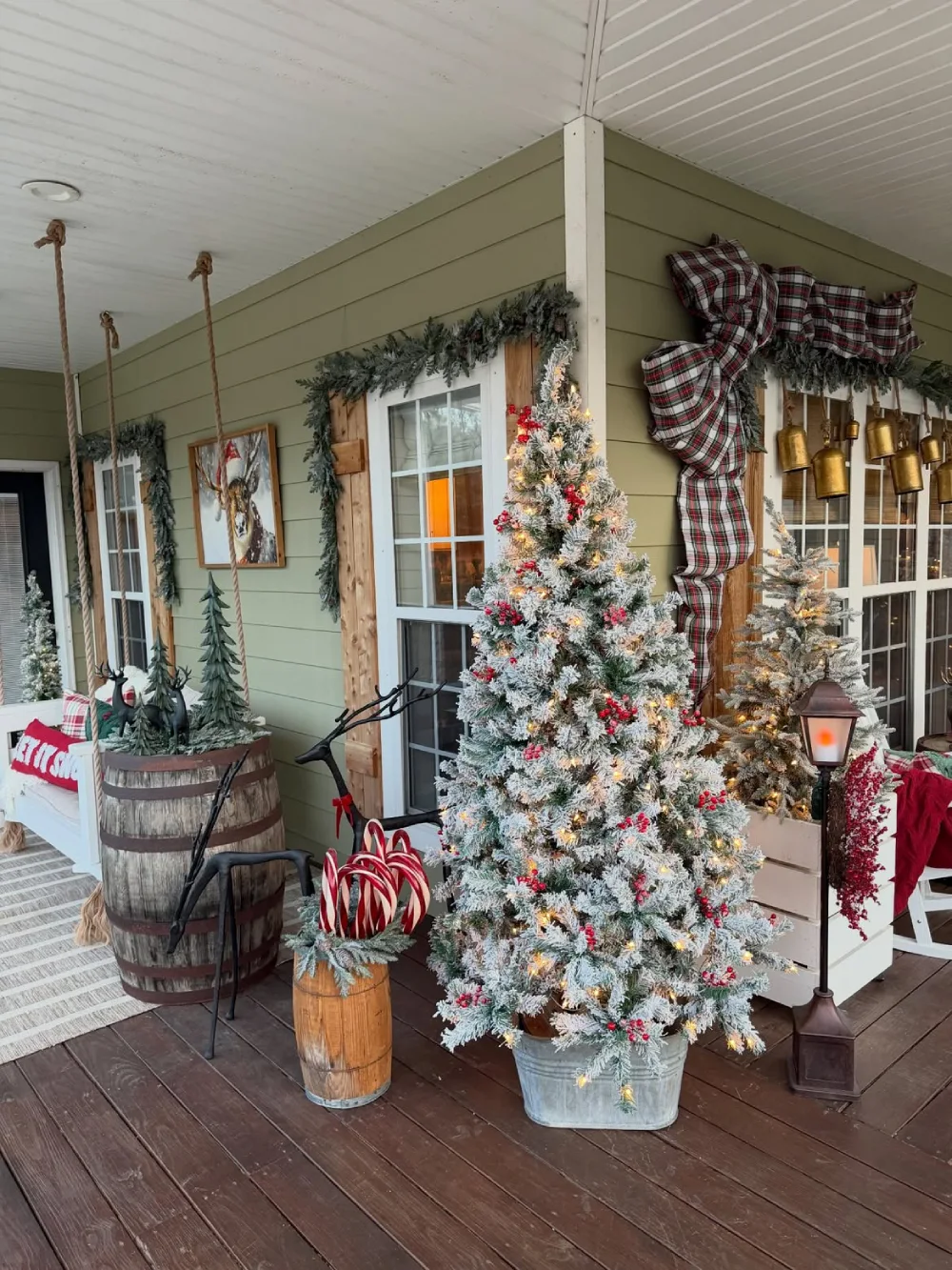 Flocked Christmas tree with red berries and warm lights on a covered porch